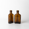 Botella alcohólica de vidrio pequeña de color ámbar plano con acabado de tornillo